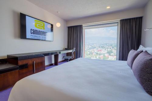 a hotel room with a large bed and a large window at Camino Real Pedregal Mexico in Mexico City