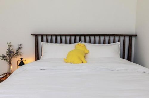 a yellow stuffed animal sitting on top of a bed at Panpo HyunStay in Jeju