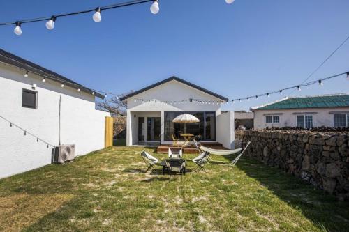 a backyard with chairs and a stone wall at Panpo HyunStay in Jeju