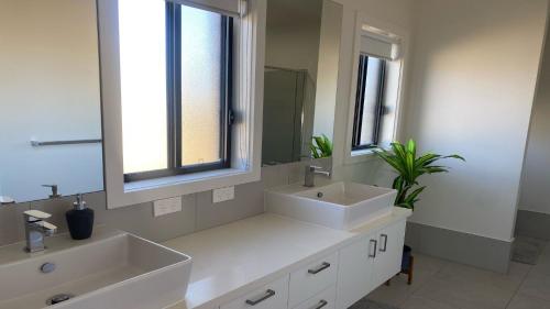- une salle de bains blanche avec deux lavabos et un miroir dans l'établissement Lakewood Drive Merimbula, à Merimbula