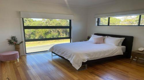 - une chambre avec un grand lit et 2 fenêtres dans l'établissement Lakewood Drive Merimbula, à Merimbula