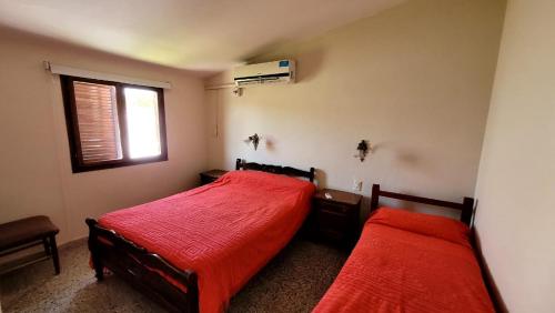 um quarto com 2 camas com lençóis vermelhos e uma janela em Departamento em Termas de Río Hondo