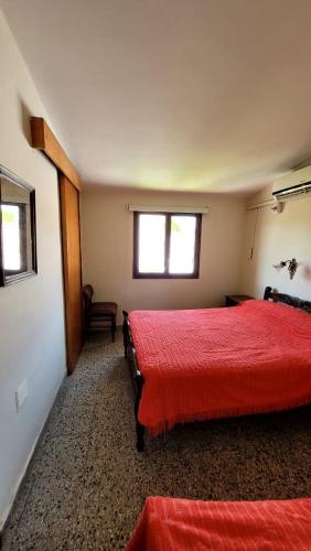 um quarto com 2 camas com lençóis vermelhos e uma janela em Departamento em Termas de Río Hondo