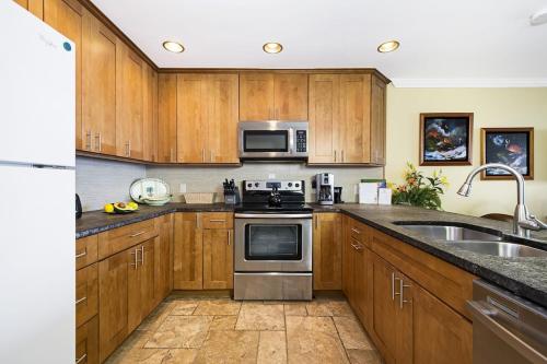 a kitchen with wooden cabinets and stainless steel appliances at Ocean Front Condo SV4207 in Kailua-Kona