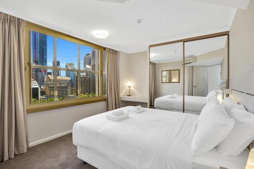 een slaapkamer met 2 bedden en een groot raam bij Apartment on Top of the Park in Sydney