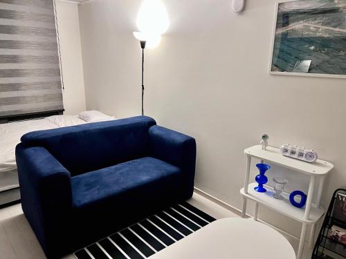a living room with a blue chair and a bed at Mi Stay - StarBnB branch in Daegu