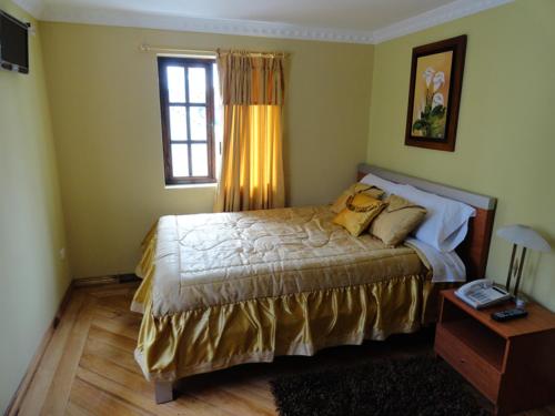1 dormitorio con cama, ventana y mesa en Hostal San Juan, en Quito