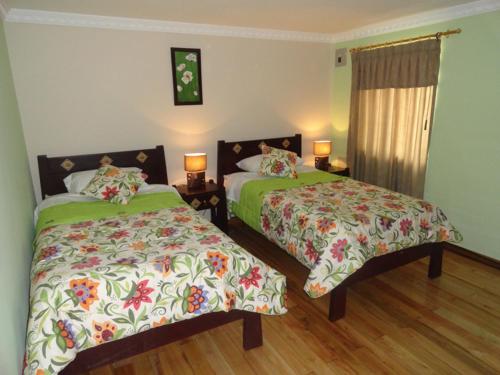 1 dormitorio con 2 camas y 2 lámparas en Hostal San Juan, en Quito