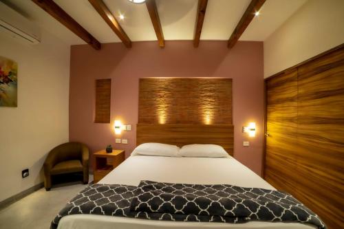 a bedroom with a large bed and a chair at Villa Guadalupe in Chapala