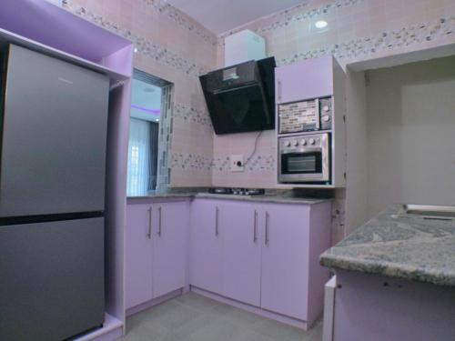 kuchnia z białymi szafkami i telewizorem na ścianie w obiekcie Vacvilla Shortlets 