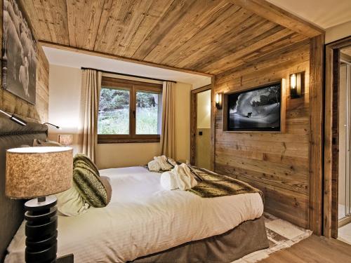 a bedroom with a bed in a room with wooden walls at Chalet Méribel, 8 pièces, 13 personnes - FR-1-613-52 in Méribel