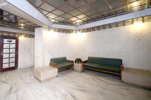 a waiting room with two green benches and a table at Capital O Hotel Kartik in Jabalpur
