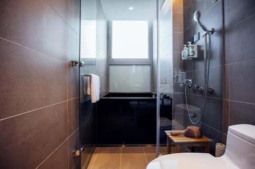 baño con ducha, aseo y ventana en Hotel BEGINS 倉箱蜜境文旅 en Keelung
