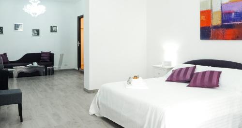 a white bed with purple pillows in a room at Etna Suite Group in Catania