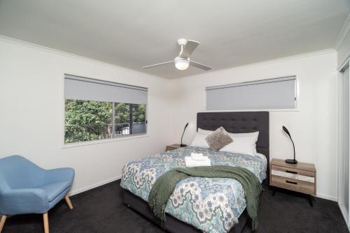 1 dormitorio con 1 cama y 1 silla azul en Little Bank House, en Mount Tamborine