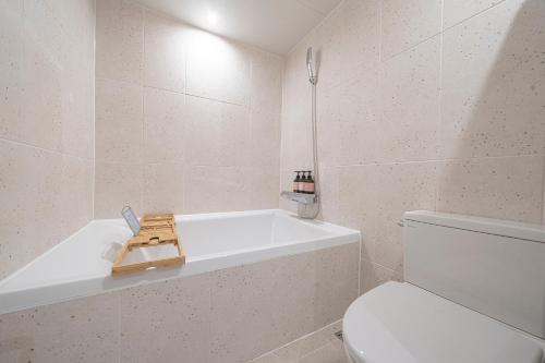 a white bathroom with a tub and a toilet at Aank Hotel Daejeon Yuseong 2nd in Daejeon