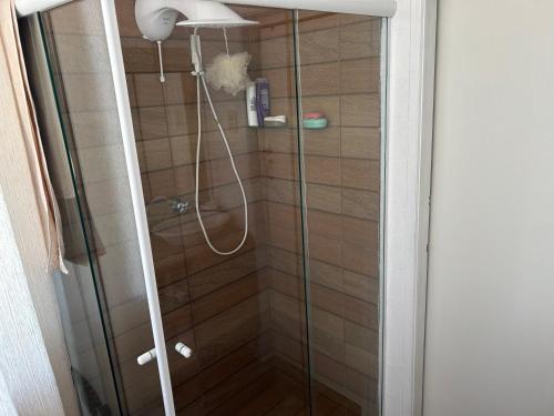 een douche met een glazen deur in de badkamer bij 8 Quarto Cama Queen e SmartTv Netflix in Itajaí