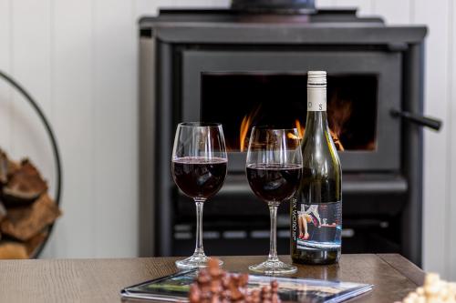 two glasses of red wine sitting on a table in front of a fireplace at Bank House Tamborine Mountain in Mount Tamborine