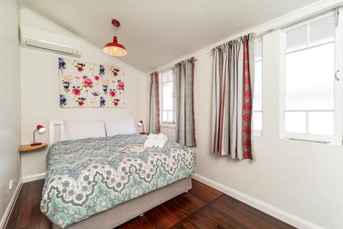 a bedroom with a bed and two windows at Bank House Tamborine Mountain in Mount Tamborine