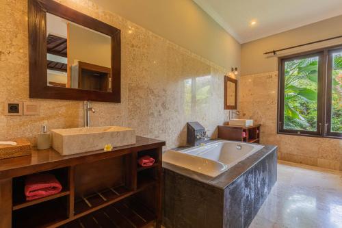 a bathroom with a large sink and a mirror at Suara Air Luxury Villa Ubud in Ubud
