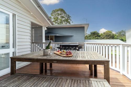 a picnic table on a deck with a grill at Bank House Tamborine Mountain in Mount Tamborine