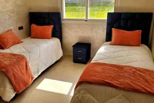 a bedroom with two beds with orange pillows and a window at New apartment with water view in El Jadida