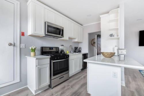 een keuken met witte kasten en een fornuis met oven bij Near NYC Luxury modern 1bed apt plus Sofa Bed & Balcony in New Rochelle