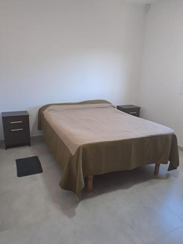 a bed in a room with two nightstands and a bedspread on it at Departamento RAWSON CALLE MITRE 956 in Rawson
