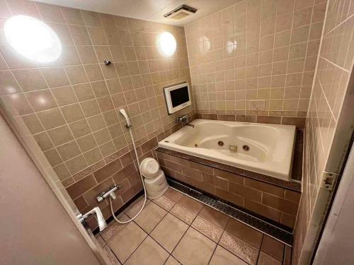 a bathroom with a tub and a toilet at HOTEL ULURU in Kobe