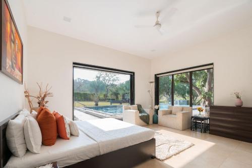 a bedroom with a bed and a living room at The Leaf by StayVista - An enchanting escape offering a pool, terrace, lush lawn, contemporary interiors, and indoor games in Alibaug