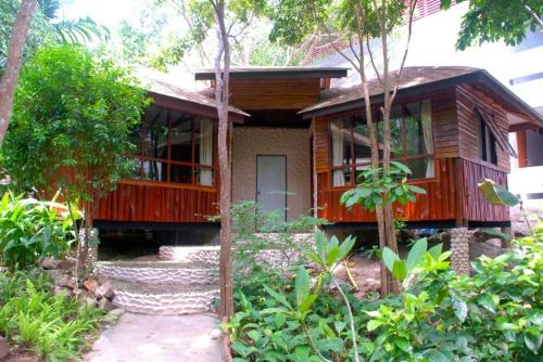 a wooden house with a porch in a garden at Montalay Beach Resort in Koh Tao