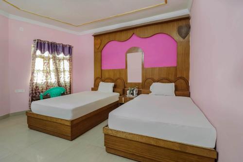 two beds in a room with pink walls at Hotel O C K International in Bodh Gaya