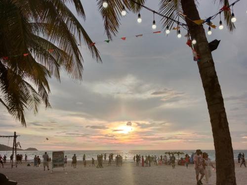 um grupo de pessoas na praia ao pôr do sol em 1919house em Praia de Patong