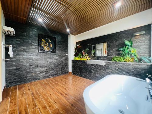ein Badezimmer mit einer weißen Badewanne und einer Ziegelwand in der Unterkunft Trippy villa: FLC Hạ Long in Hạ Long