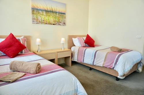 a bedroom with two beds with red pillows on them at Beach Haven in Point Lonsdale