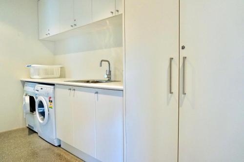 a kitchen with a sink and a washing machine at Beach Haven in Point Lonsdale
