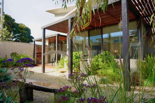 a house with glass windows and flowers in front of it at Beach Haven in Point Lonsdale