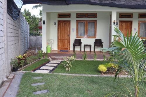 a house with a yard with chairs in front of it at Room 212 in Kuta Lombok