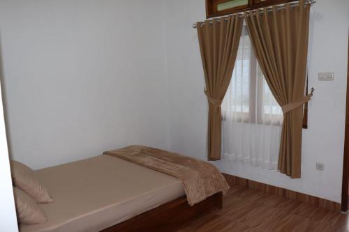 a small bedroom with a bed and a window at Room 212 in Kuta Lombok