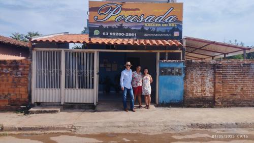 a man and two women standing in front of a building at Pousada Auroranascerdosol in Manhã
