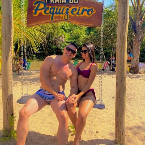 a man and a woman sitting on a swing at the beach at Pousada Auroranascerdosol in Manhã