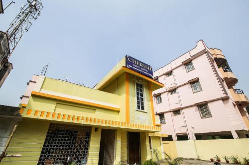 兰奇SPOT ON Cherish Guest House的黄色的建筑和粉红色的建筑,上面有标志