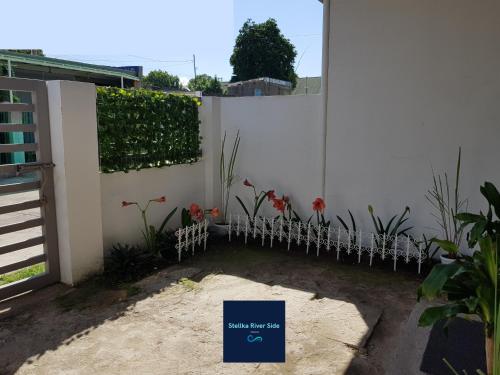 a white fence with red flowers in a yard at Stellka cheerful 2BR townhouse near the beach and city in Nasugbu