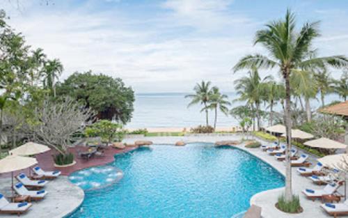 a swimming pool with chairs and umbrellas at a resort at Sea Sand Sun Resort and Villas - SHA Plus in Na Jomtien