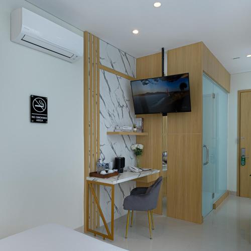 een kamer met een bureau en een tv aan de muur bij The Risman Hotel At Jakarta Airport CBC in Tangerang