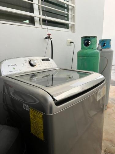 eine Waschmaschine in einem Zimmer mit einer grünen Vase in der Unterkunft Casa Flor de Mayo, fresca, climas, en privada in Mérida