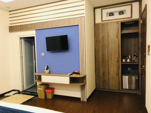 邦美蜀Huyen Nga Hotel的一间客厅,客厅的蓝色墙壁上配有电视