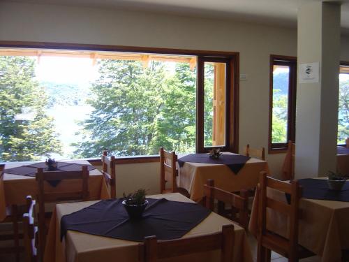 a restaurant with tables and chairs and a large window at Peninsula de los Coihues in Villa Pehuenia
