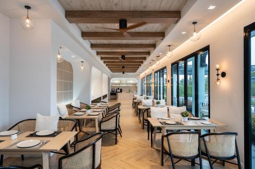 a restaurant with tables and chairs and windows at Estella Khao Yai in Khao Yai