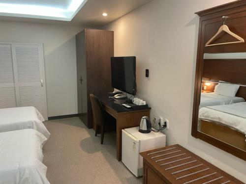 1 dormitorio con escritorio, TV y cama en Incheon Airporthotel Airstay, en Incheon